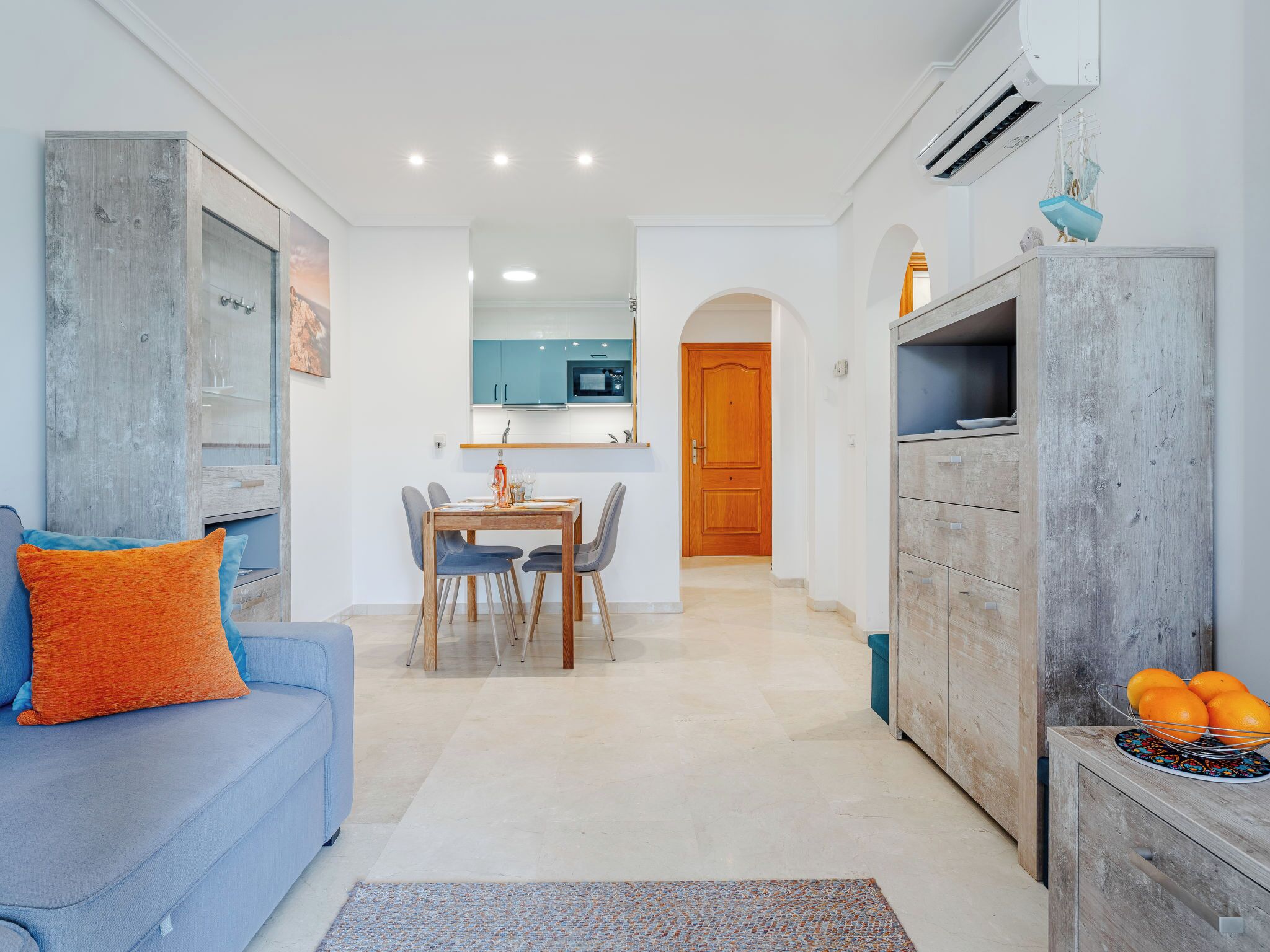 A modern living room with a sofa, dining table, and kitchen area.