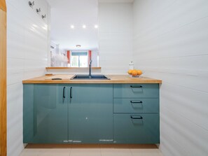 A kitchen with a sink, a window with curtains, and a bowl of fruit on the counter. - Jardines del Rio by Interhome (Jávea)