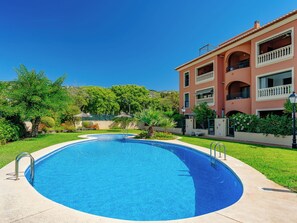 A swimming pool with a clear blue water, surrounded by a well-maintained lawn and a building with balconies. - Jardines del Rio by Interhome (Jávea)