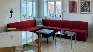 A modern living room with a red sofa, a round table, and a yellow pendant light. - Classic apartment with a balcony in Amagerbro (København)