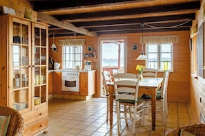 A wooden cabin interior with a kitchen, dining table, and chairs. - Nature gem 5 metres from Limfjord (Roslev)