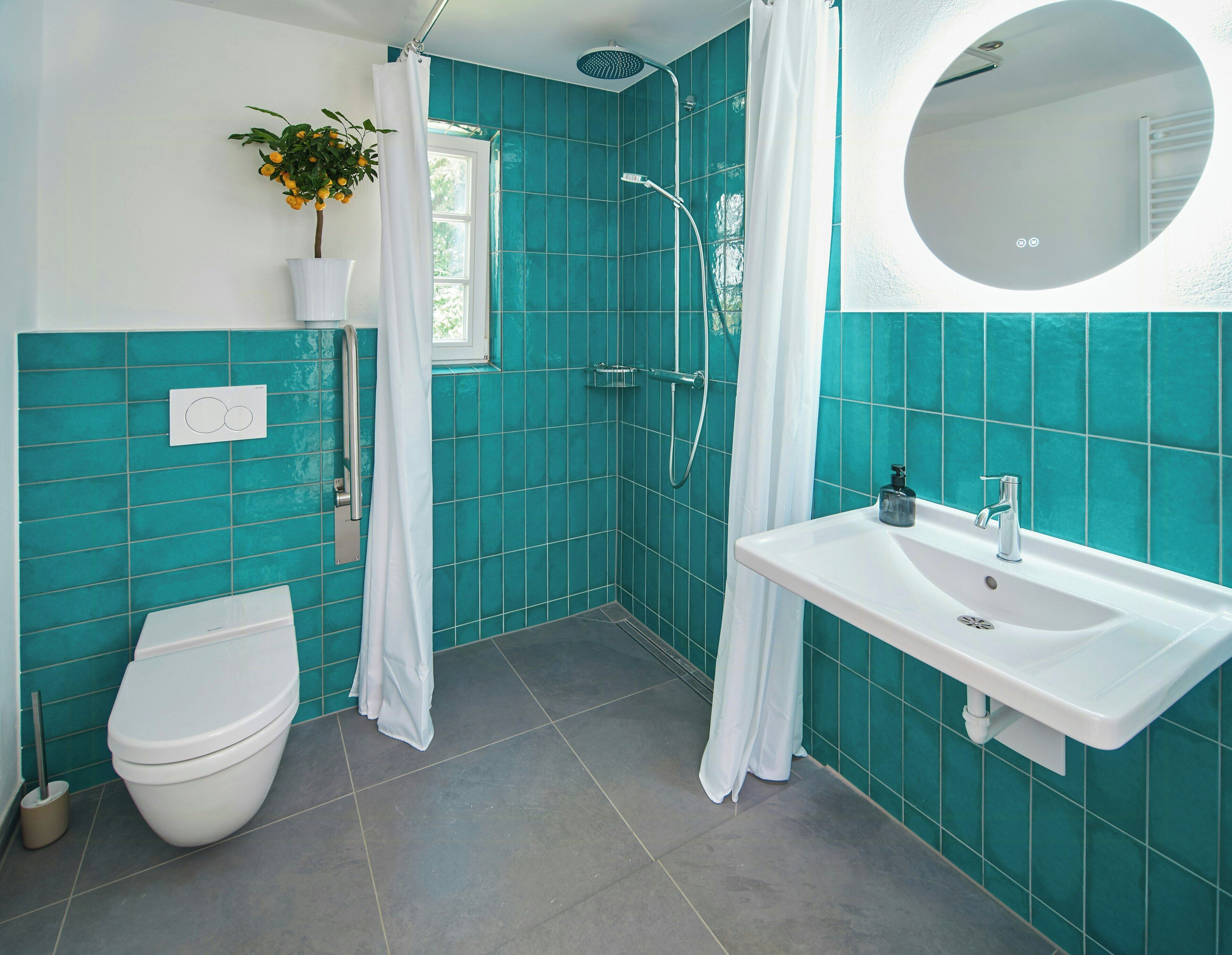 A bathroom with a toilet, sink, shower, and a potted plant.