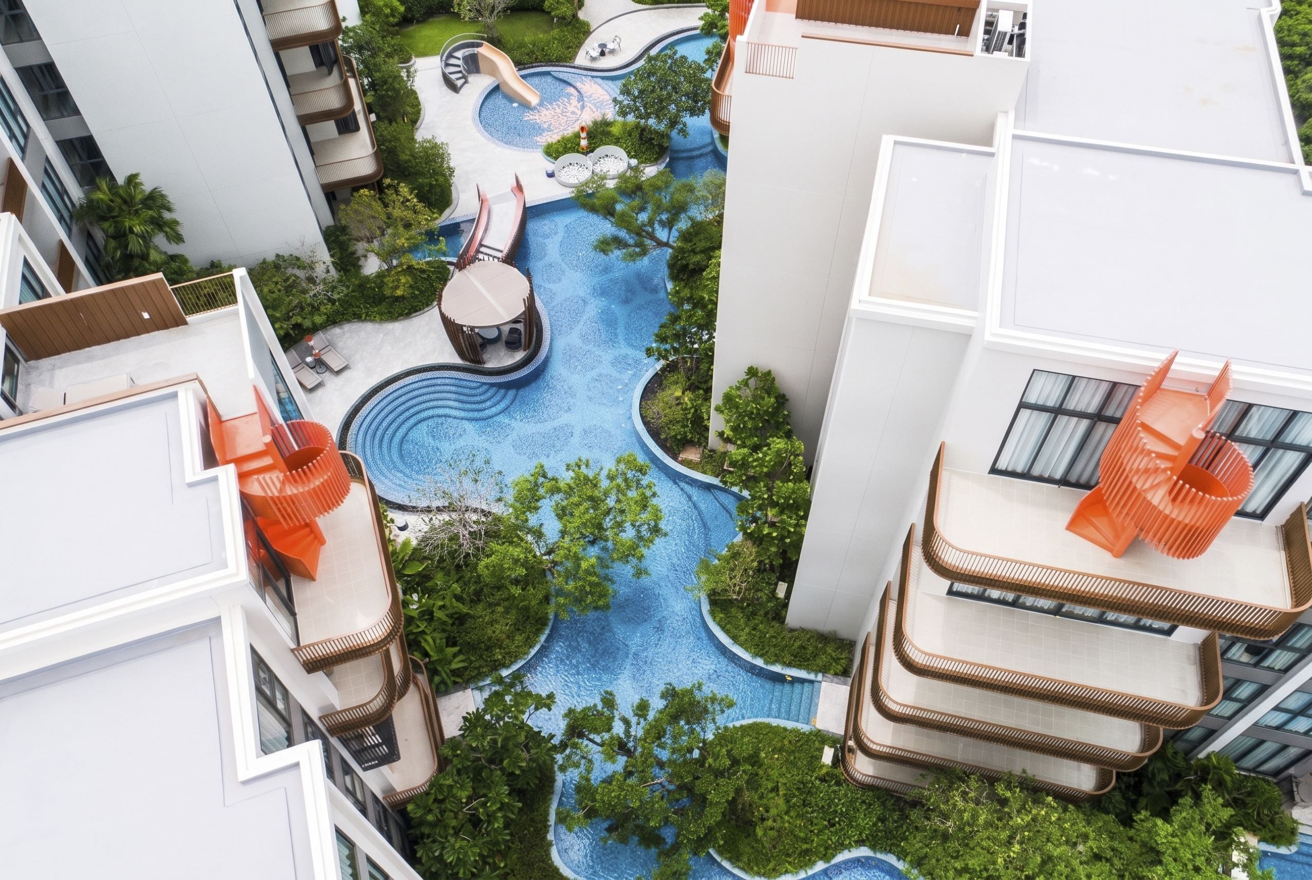 A residential building with a swimming pool, outdoor seating, and lush greenery.