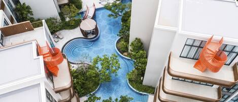 A residential building with a swimming pool, outdoor seating, and lush greenery.