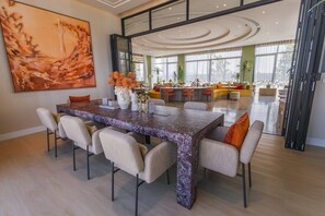 A spacious living area with a large dining table, comfortable seating, and a large abstract painting on the wall. - Bright 2-bedroom apartment in center of Bangtao (Tambon Choeng Thale)