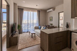 A modern apartment with a living area, kitchenette, and a balcony with a city view. - Bright 2BR Apartment in Central Bang Tao (Choeng Thale)