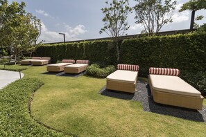Un jardín con mobiliario exterior y un seto.