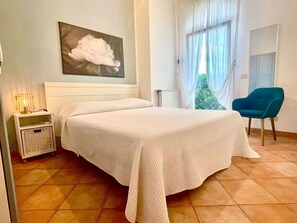 Una camera da letto con un letto, un comodino, una sedia e una finestra con tende.