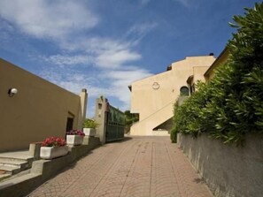 Un camí pavimentat que condueix a un edifici amb façana beix i un rellotge al mur.