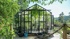 A greenhouse with a wooden deck, potted plants, and a table with chairs. - 1929 villa with pool and spa by Lake Hällungen (Svenshögen)