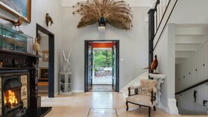 A grand hallway with a fireplace, a peacock feather decoration, and a staircase. - 1929 villa with pool and spa by Lake Hällungen (Svenshögen)