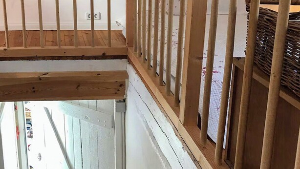 Una scala con ringhiera in legno e pareti bianche.
