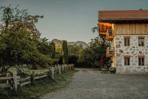 Un bâtiment en pierre doté d’un balcon en bois, d’un chemin de gravier et d’une clôture en bois.