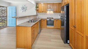 Una cocina con armarios de madera, un refrigerador de acero inoxidable, un horno y un lavamanos.