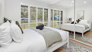 Un dormitorio moderno con una cama grande, un espejo y vistas al exterior.