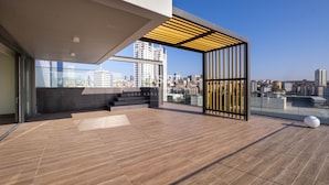 En takterrass med utsikt över stadens silhuett, en pergola och en modern arkitektonisk design.