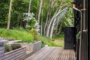 A wooden deck with a garden area, a black door, and a water feature. - Summerhouse close to nature by The Limfjord (Nykøbing Mors)