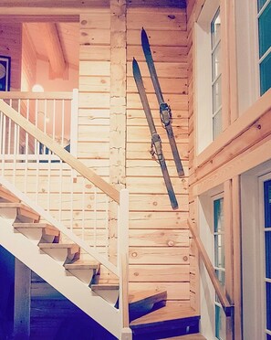 Un escalier en bois avec une rampe, une fenêtre et une paire de skis accrochés au mur.