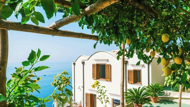 A coastal building with a balcony overlooking the sea, surrounded by greenery and potted plants. - Baroque house with lemon groves in Amalfi (Amalfi)