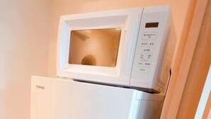 Eine kleine Küche mit einem Edelstahlkühlschrank und einer Mikrowelle darüber.