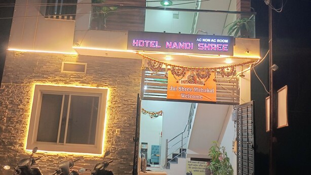 A hotel entrance with a neon sign, a staircase, and parked motorcycles.