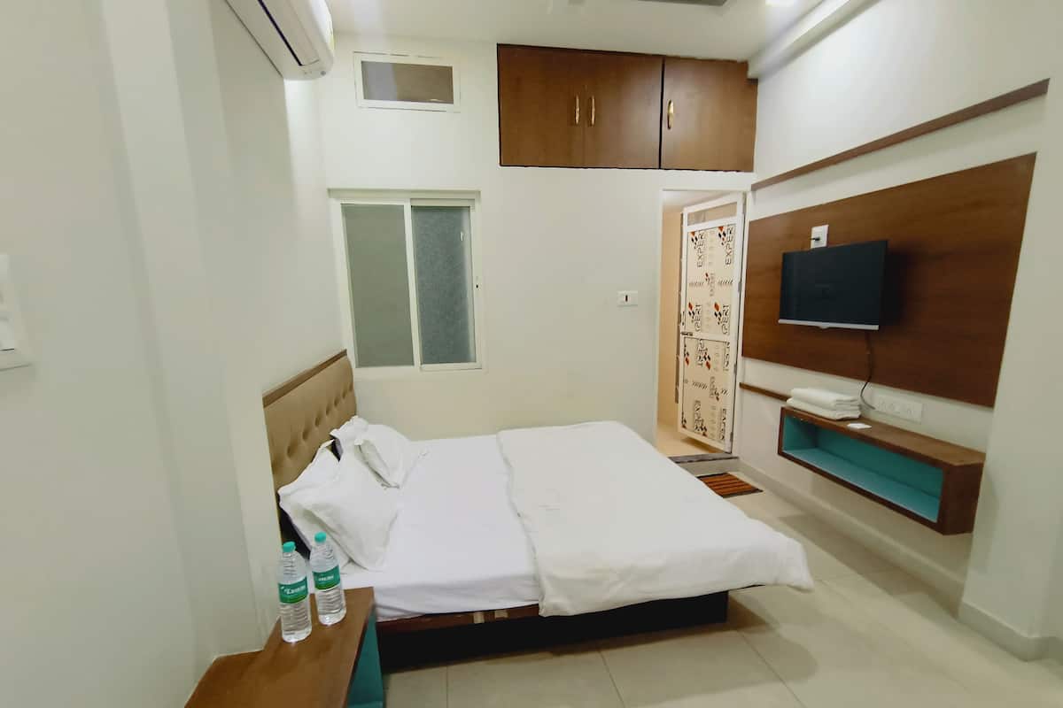 A hotel room with a bed, a TV, a wardrobe, and a window.