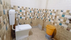 A bathroom with a toilet, a shower, and a yellow bucket.