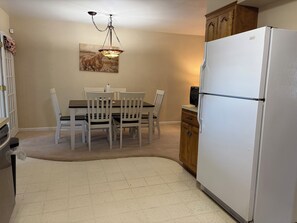 A kitchen with a dining table, chairs, a refrigerator, and a hanging light fixture. - Stay at our spacious 4-bedroom 2 bathroom house in Childress with AC. (Childress)