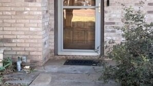 A brick building with a glass door and a small porch area.