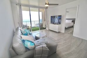 Una habitación de hotel moderna con balcón, un sofá, un televisor y una cama.