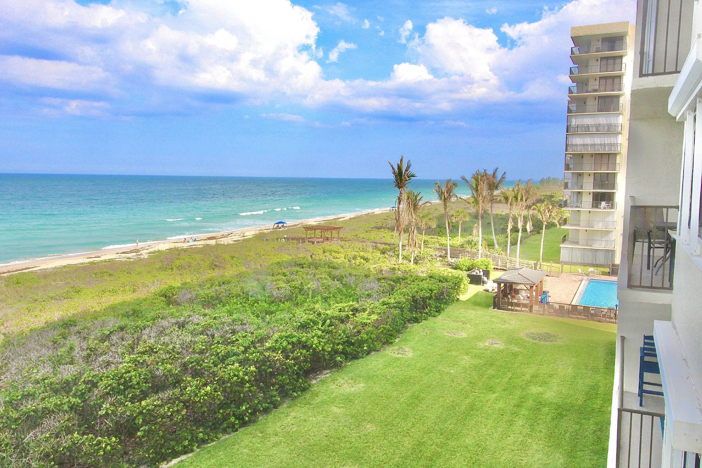 A view of a beach with a pool and a building with balconies.
