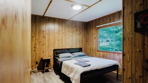 Ein Zimmer mit Holzwänden, einem Bett, einem Fenster und einer Tür.