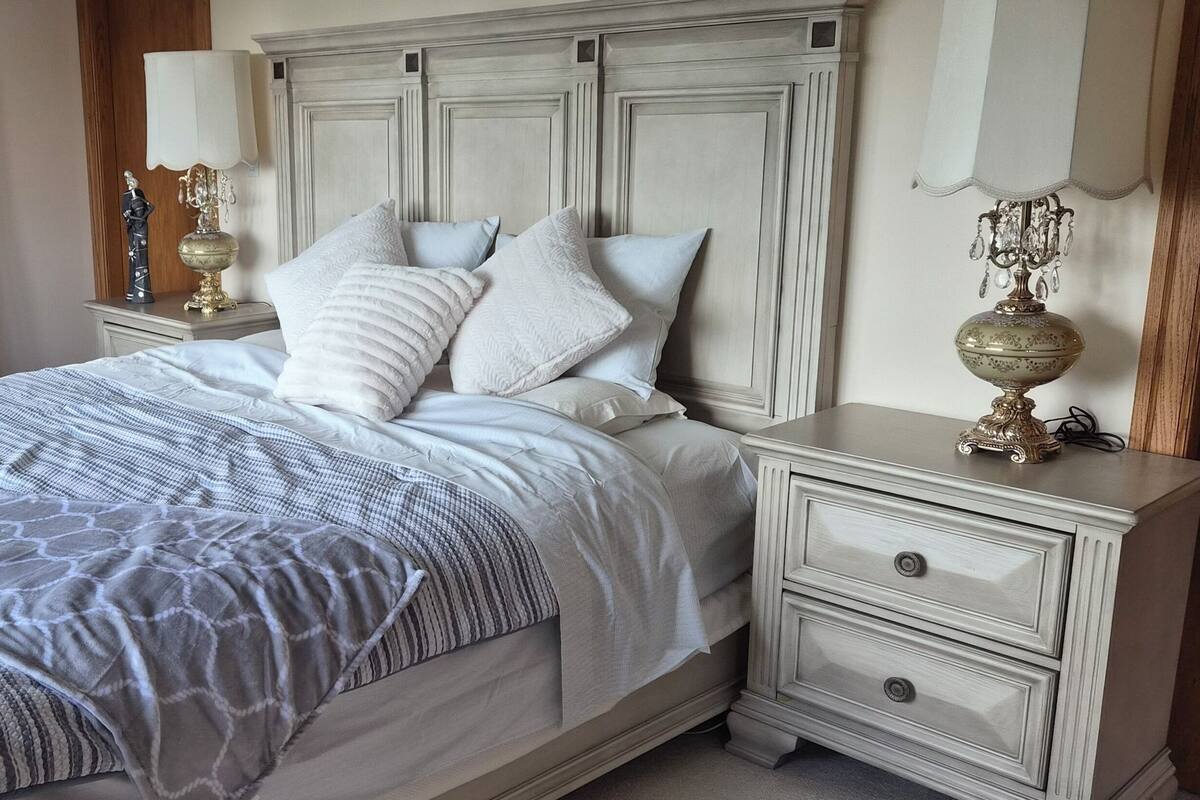 Un dormitorio con cama, mesitas de noche y cómoda.