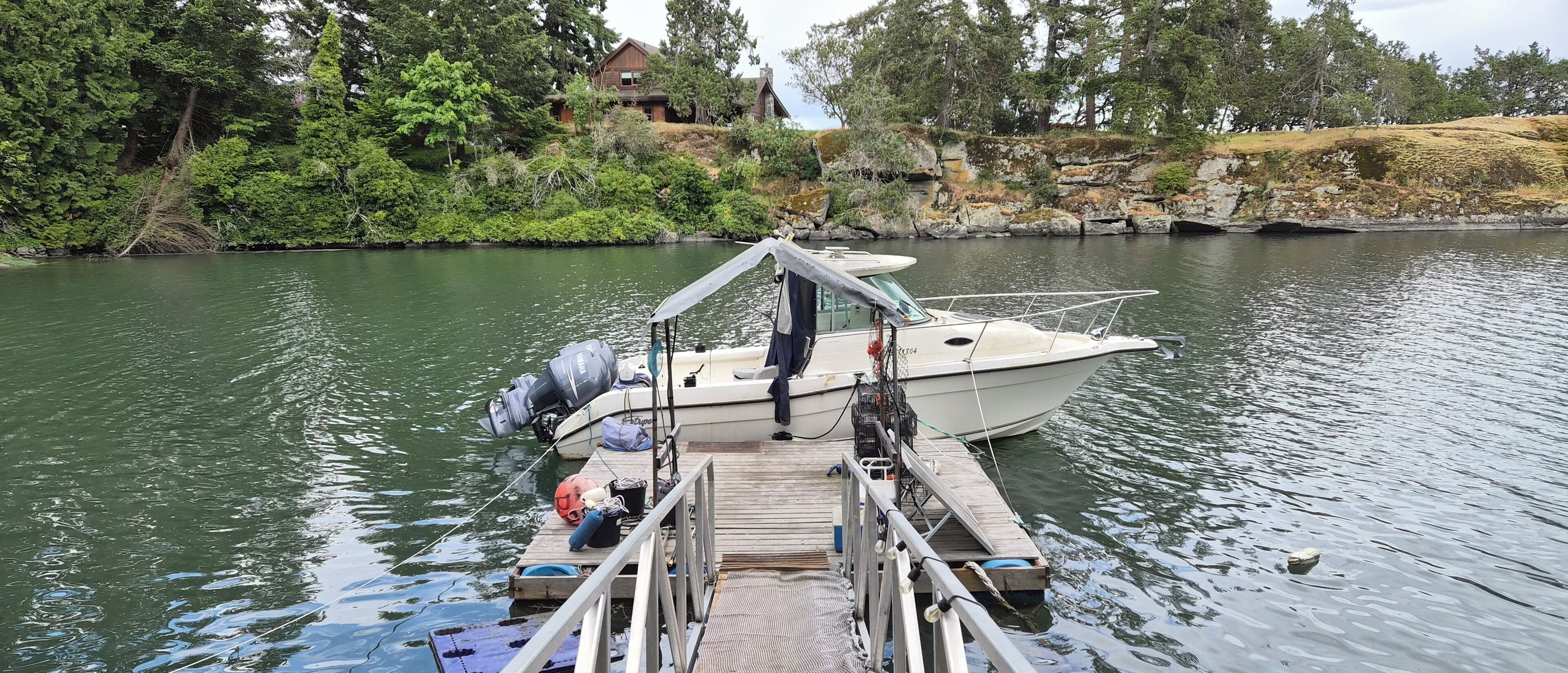 Un bote amarrado en un muelle, con una casa al fondo.