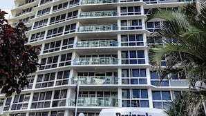 A high-rise building with multiple balconies, a clear sky, and a sign reading 'Peninsula'. - Drift n Dream Apartment w/Free Parking+Pool+Gym (Surfers Paradise)