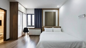 Ein Hotelzimmer mit Bett, Schreibtisch, Stuhl, einem Fenster mit Vorhängen und einem Fernseher.