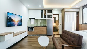 Um espaço de estar moderno com televisão de tela plana, um sofá, uma mesa de jantar e uma cozinha.