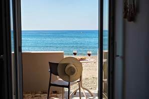 Ein Balkon mit Meerblick, zwei Gläser Rotwein und ein Korbstuhl.