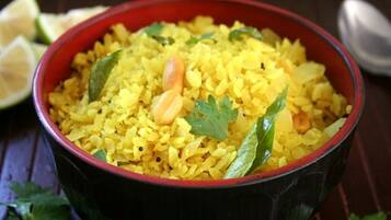 Un tazón de arroz amarillo adornado con hierbas y verduras.