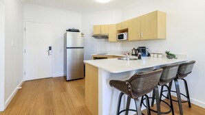 Una cocina compacta con refrigerador, microondas y una pequeña isla con taburetes de bar.