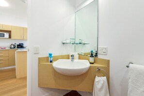 A modern bathroom with a white sink, a large mirror, and a towel rack. - Resort Escape: King Bed, Pool & Balcony (Darwin City)