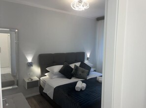Une chambre d’hôtel avec un lit, des tables de chevet, un miroir et un lustre.