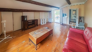 A spacious living area with wooden flooring, a red leather sofa, a wooden coffee table, and a television on a wooden cabinet. - Gorgeous apartment in Cessenon-Sur-Orb with WiFi (Cessenon-Sur-Orb)