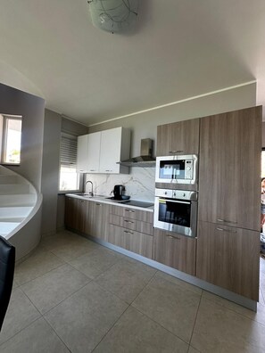 A modern kitchen with a built-in oven, microwave, and a coffee maker on the countertop.