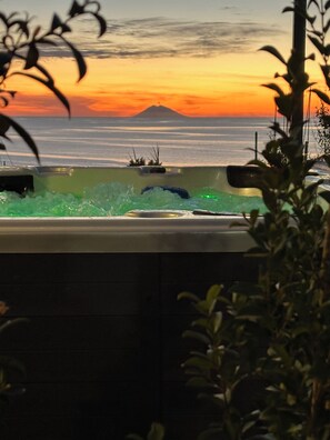 Un jacuzzi con vistas a un atardecer y una montaña al fondo.