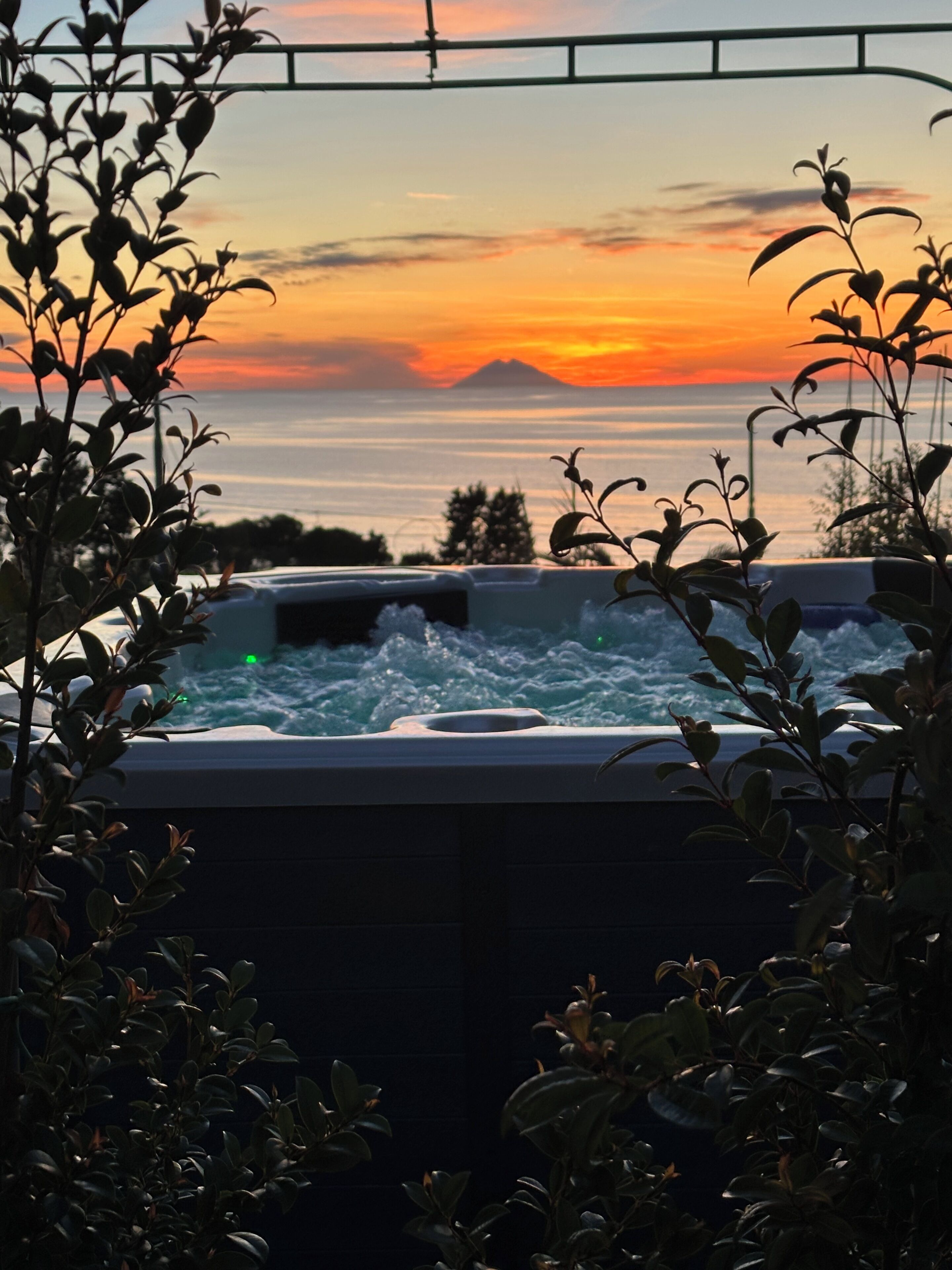 A hot tub with a view of the ocean and a sunset.
