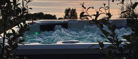 A hot tub with a view of the ocean and a sunset.