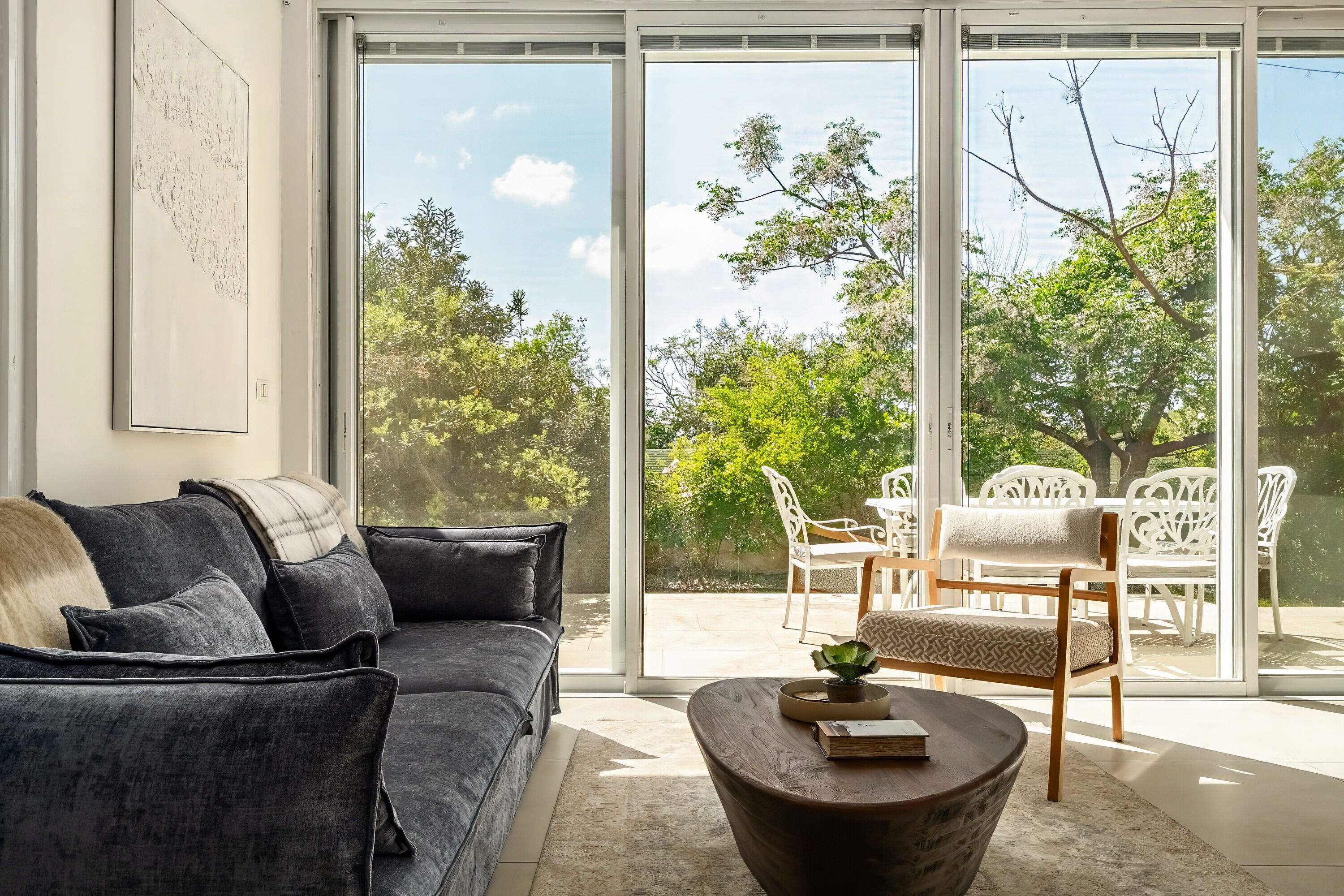 A modern living room with a sofa, a coffee table, and a view of an outdoor patio area.