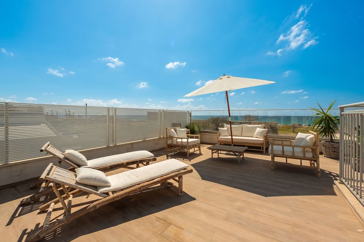 Terraza en la azotea con sillones, una mesa y una sombrilla.