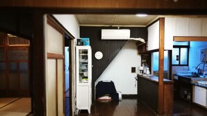 Un pasillo estrecho con piso de madera, un refrigerador blanco, un microondas y una pequeña área de cocina con un lavamanos y armarios.
